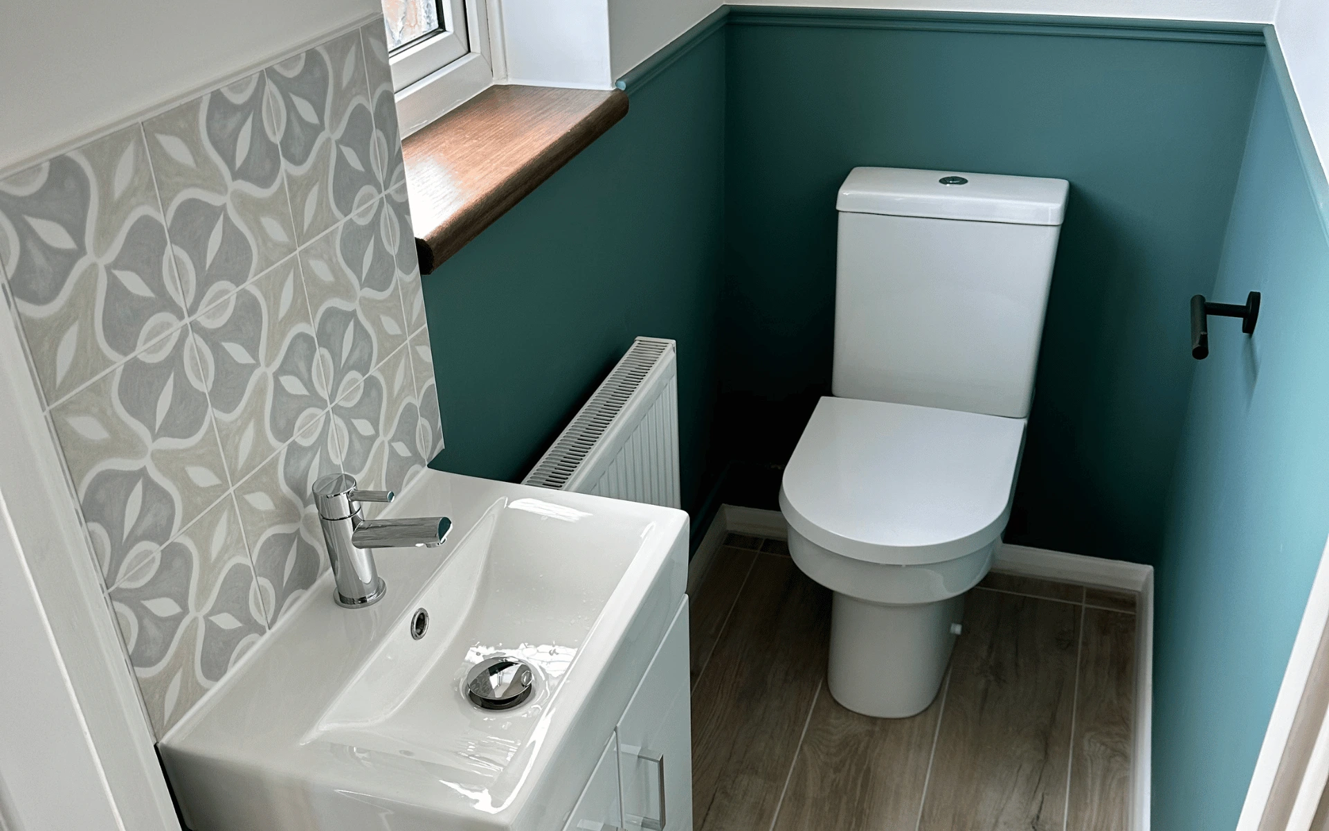 Modern cloakroom renovation in Taunton featuring a vanity basin, contemporary toilet, patterned feature tiles and sage green wall panelling completed by Plumb Inc.